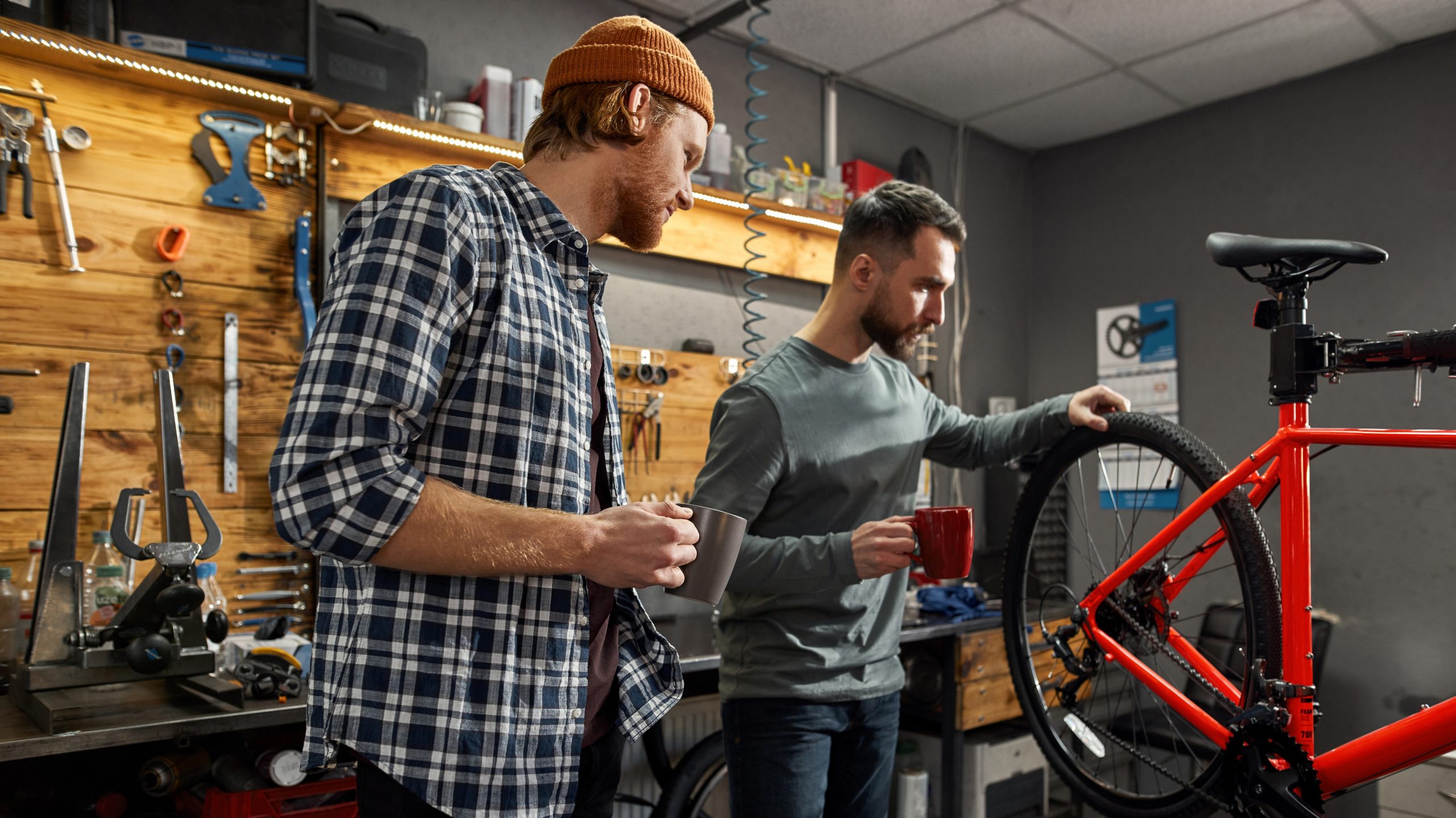 Two bicycle repair shop employees inspect the wheel of a mounted bike